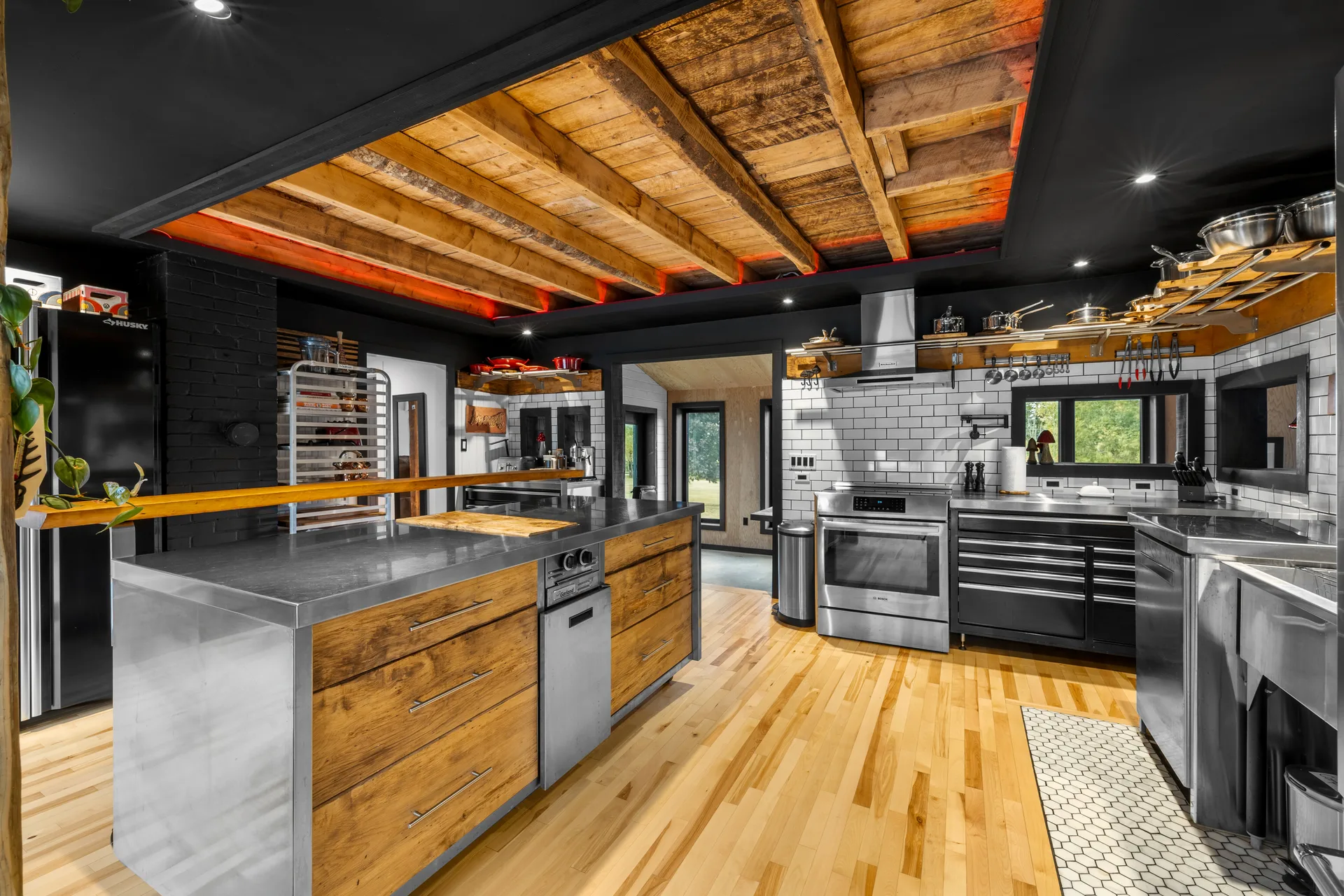 Rustic-modern kitchen with stainless steel island, natural wood cabinetry, and exposed wooden beams