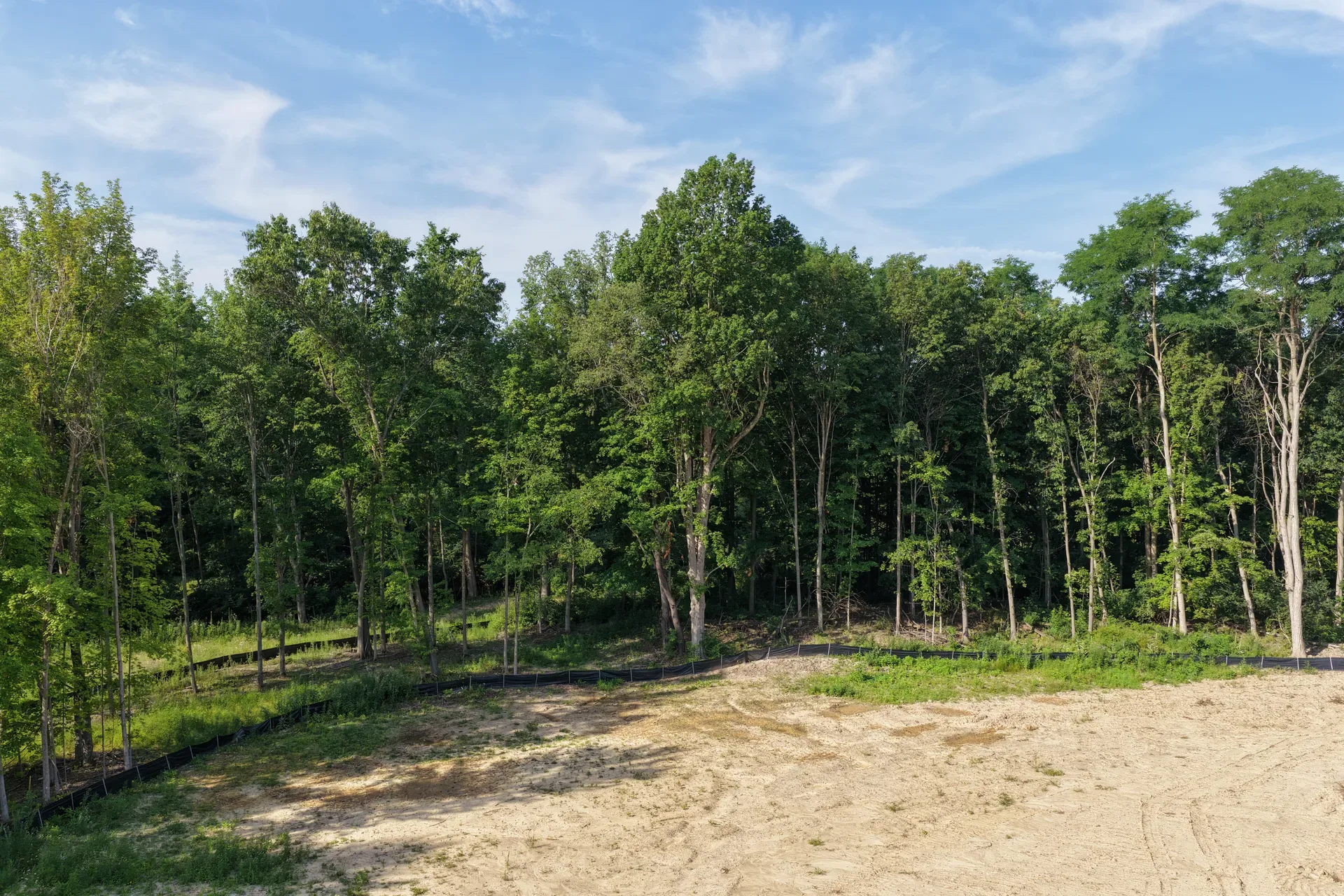 Drone aerial of a wooded construction lot at Oaks of Tyrone with survey stakes and grading in progress