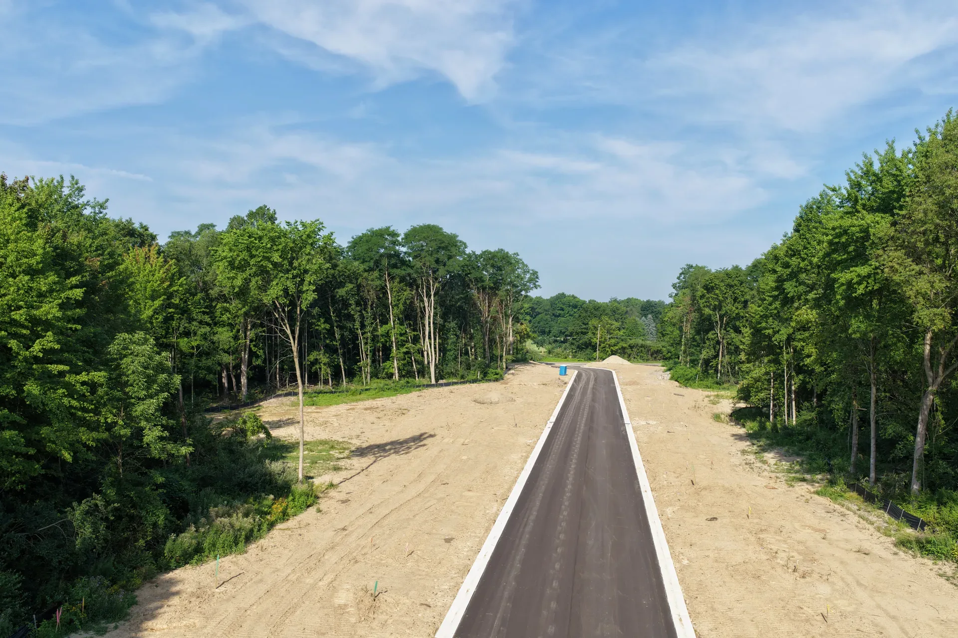Drone view of a new access road cut through the woods at Oaks of Tyrone providing entry to interior homesites