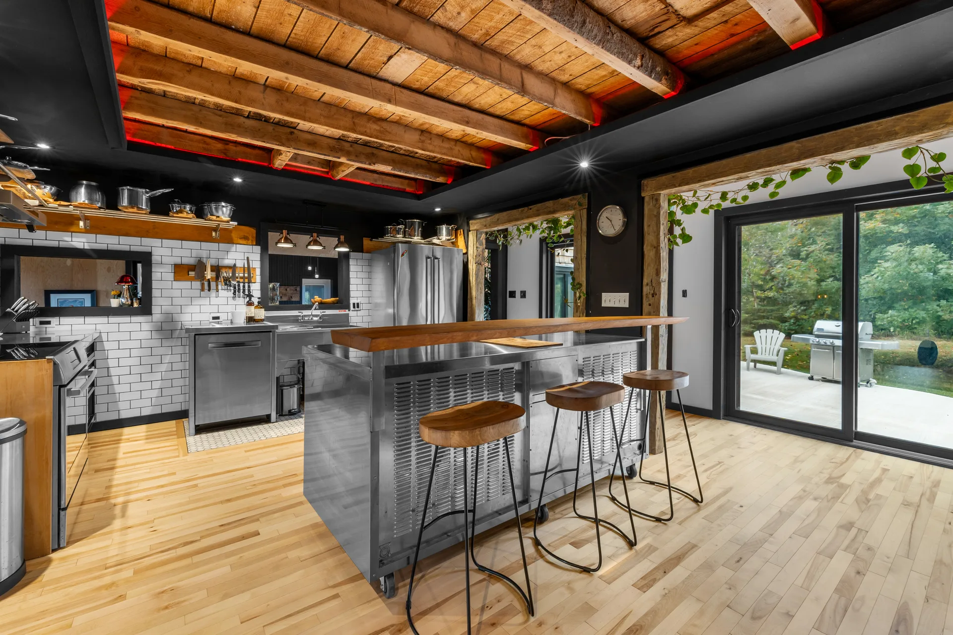 Chef's kitchen with stainless steel island, exposed wood beams, and white subway tile backsplash