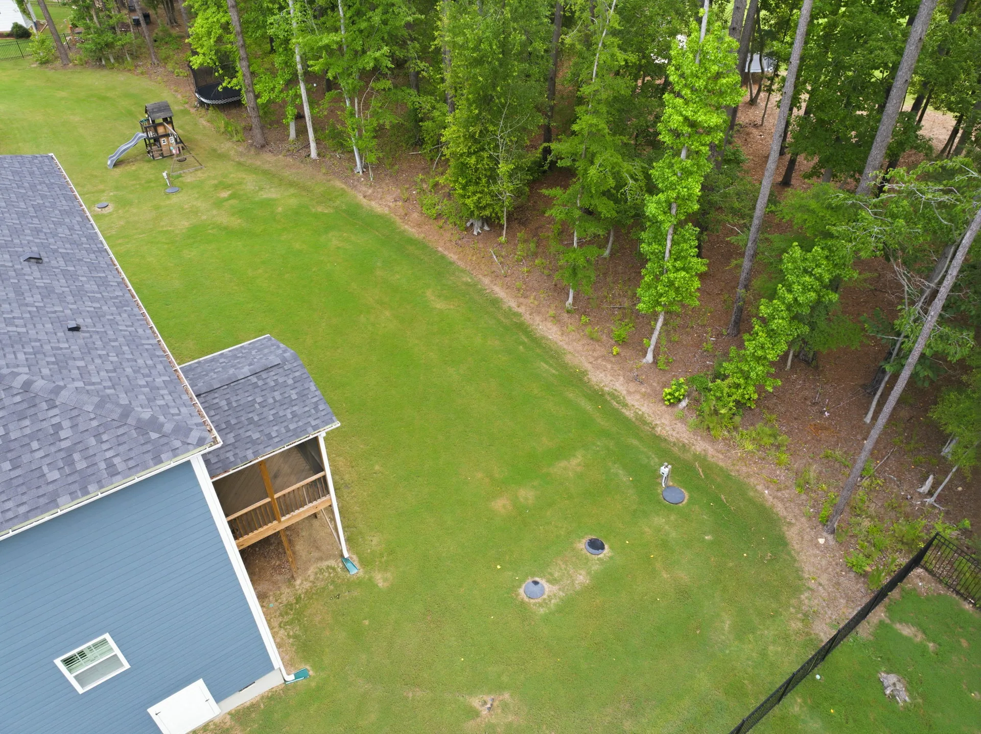Aerial view of backyard with lawn and tree boundary