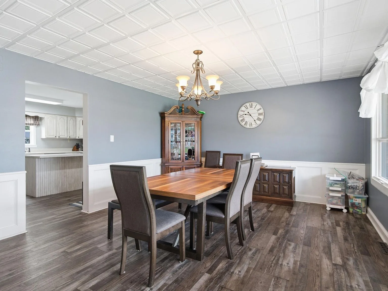 Formal dining room with grey walls, white wainscoting, and chandelier