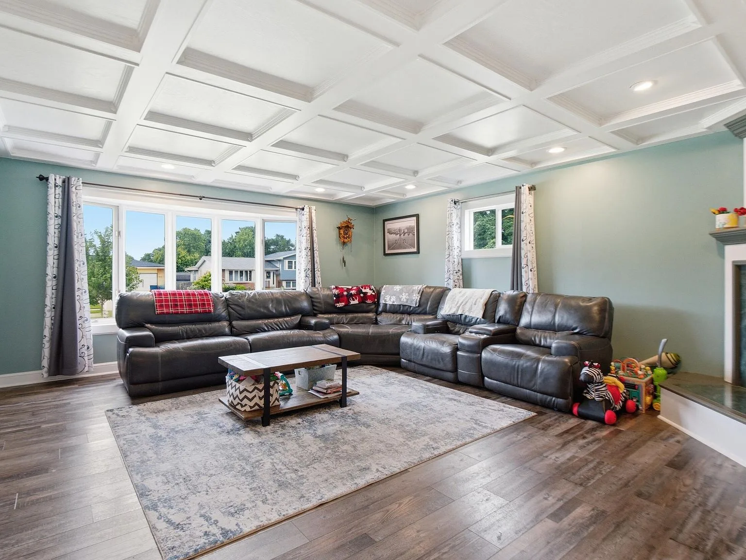 Living room with coffered ceiling, fireplace, and bay window