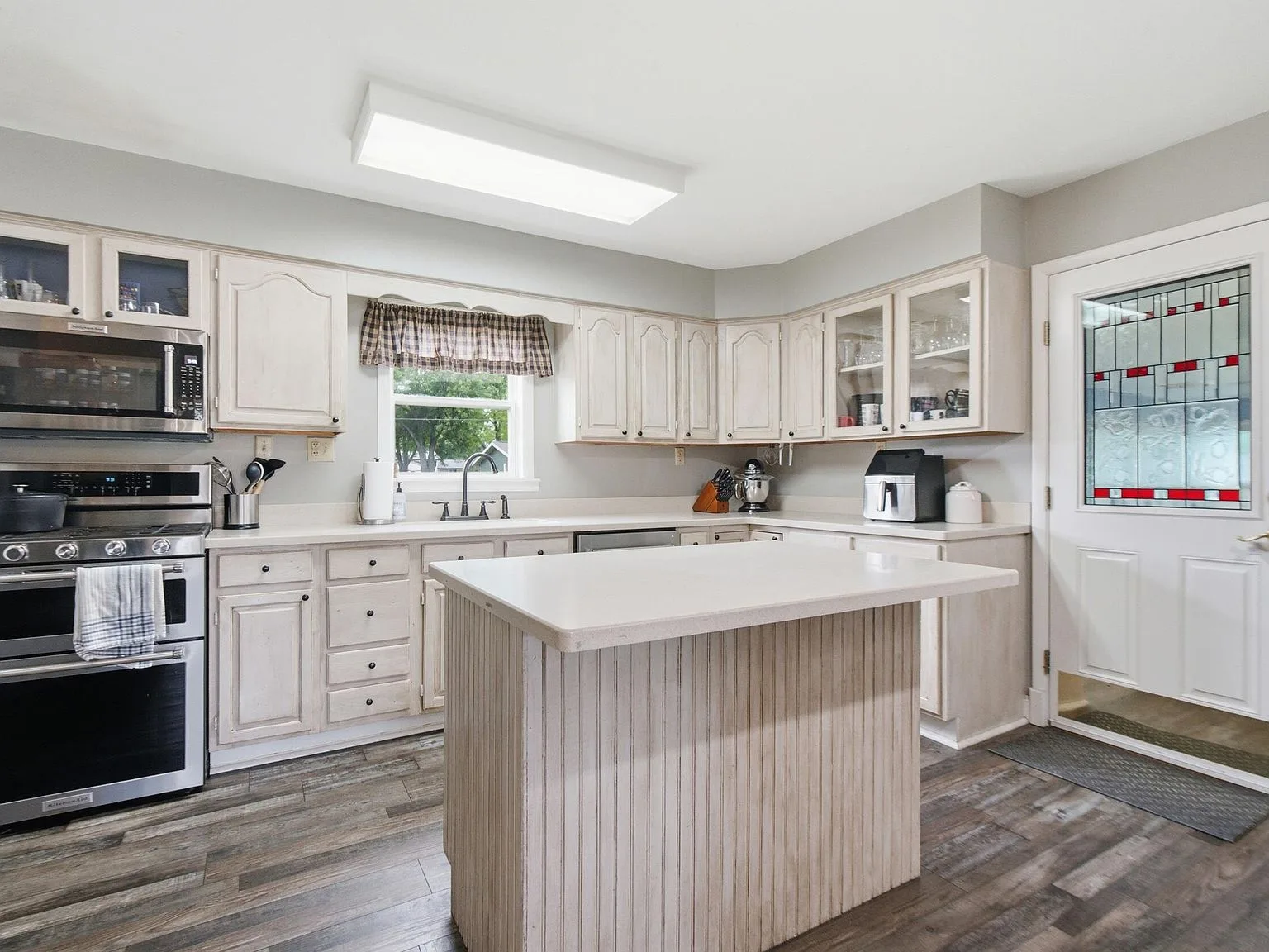Updated kitchen with white cabinetry, stainless steel appliances, and island