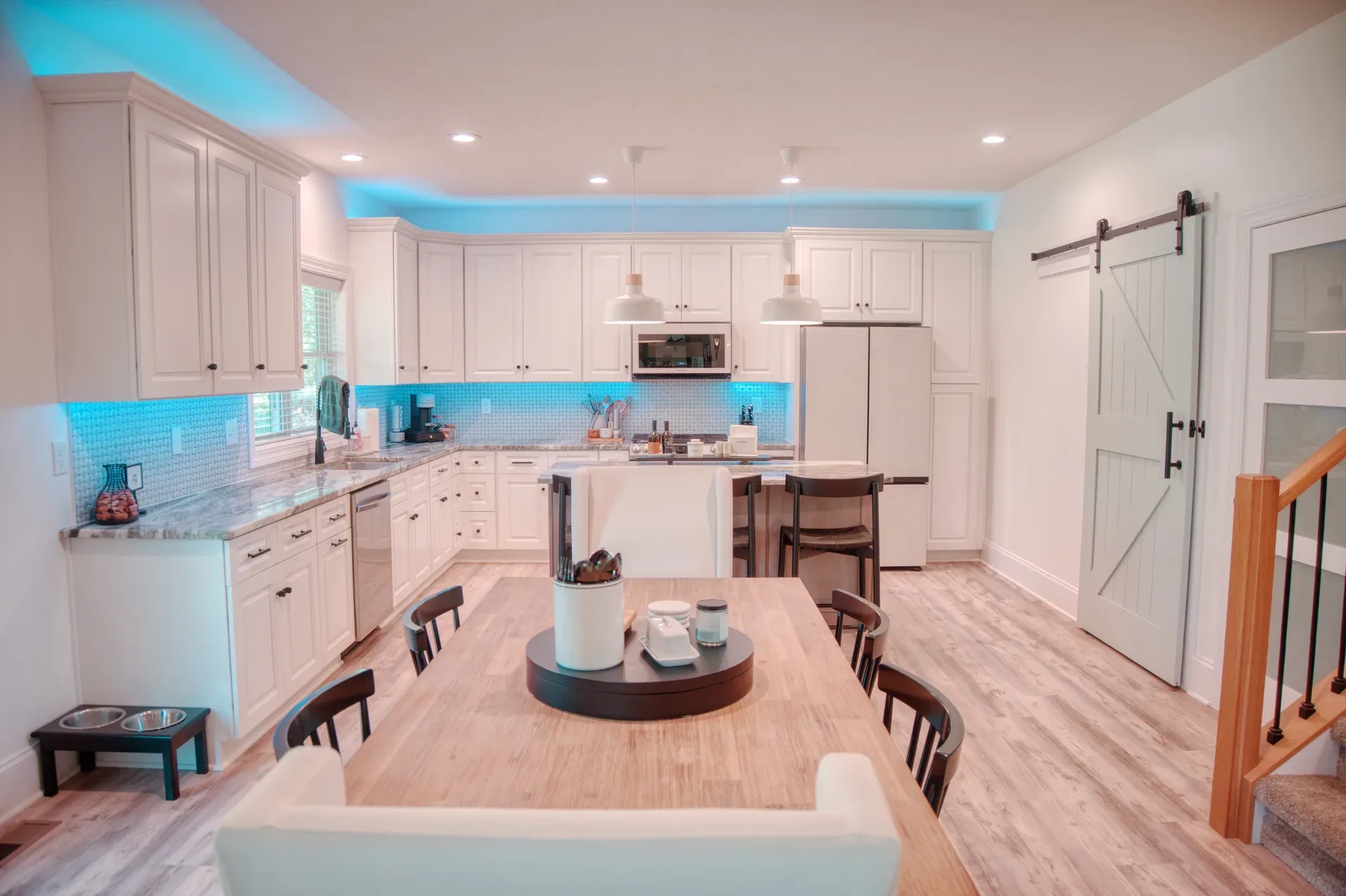 Open-concept kitchen and dining area with island, blue barn door, and LVP flooring