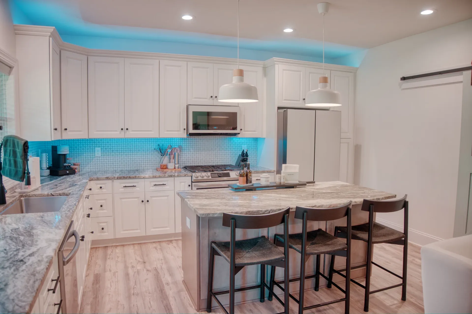 Modern white kitchen with island barstools, pendant lights, and Samsung Bespoke appliances