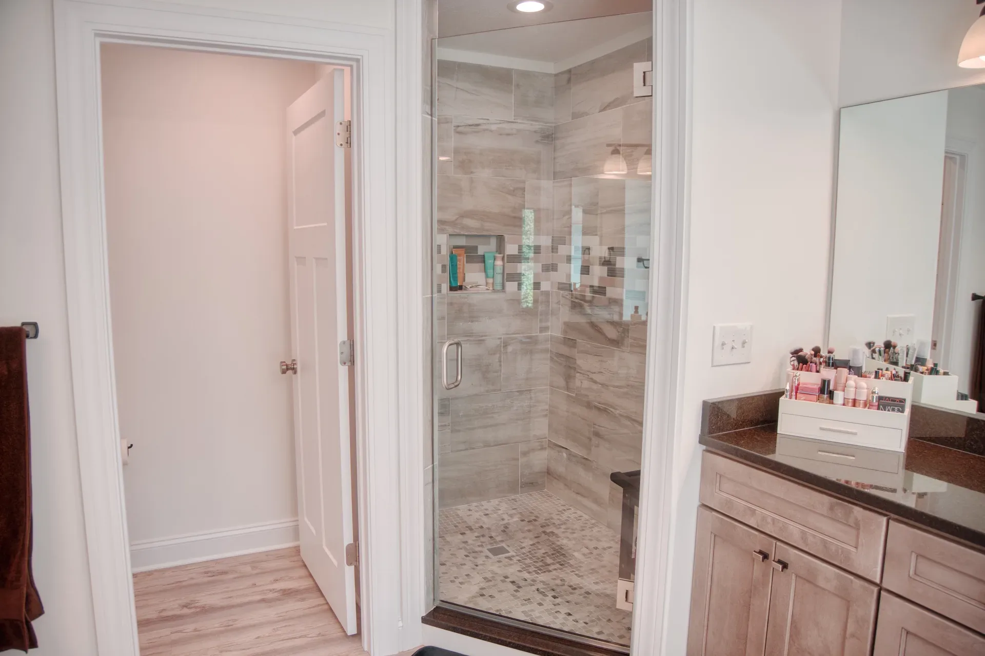 Master bathroom walk-in tiled shower with glass enclosure and pebble floor