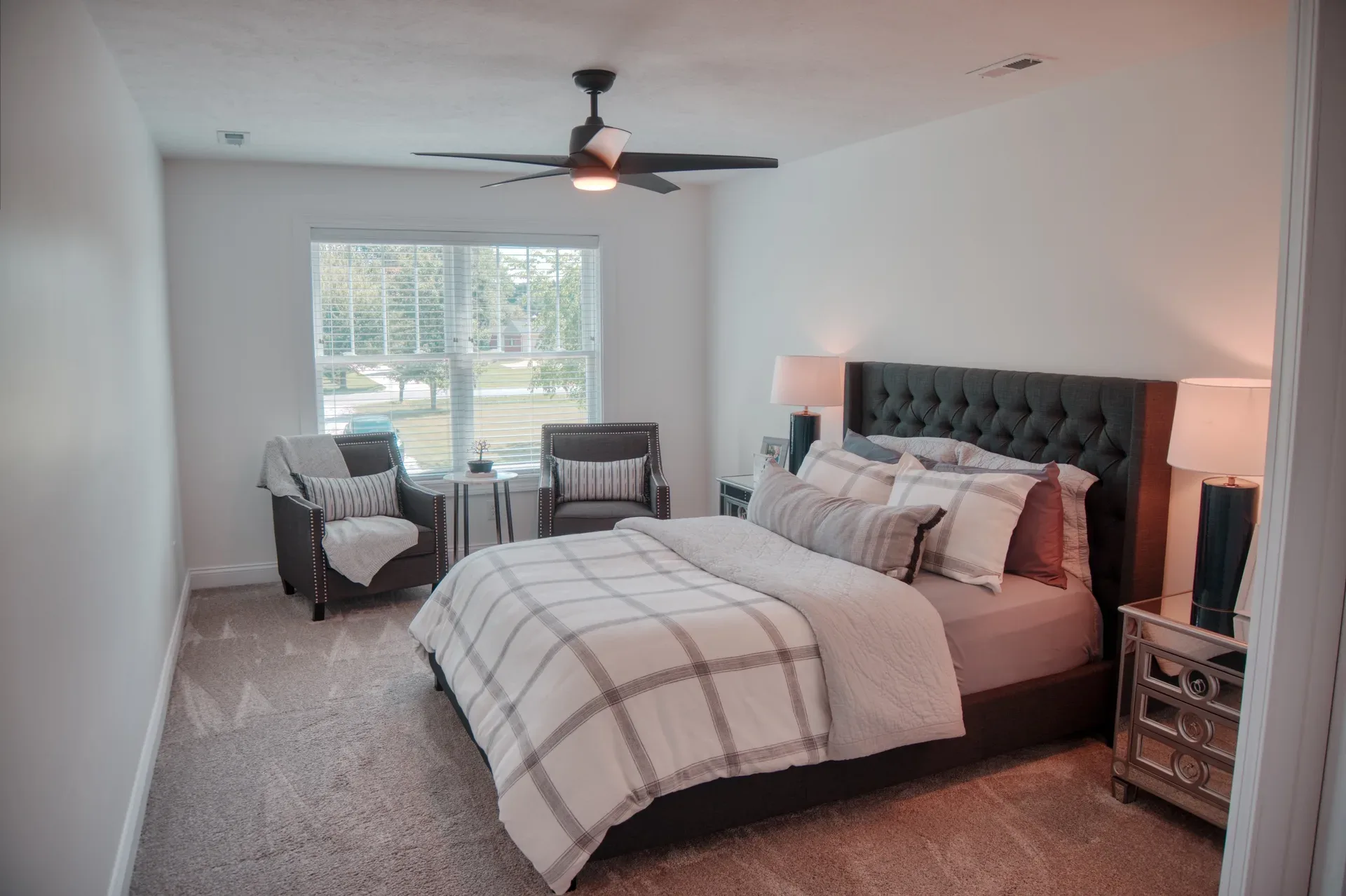 Master bedroom with tufted grey headboard and large window