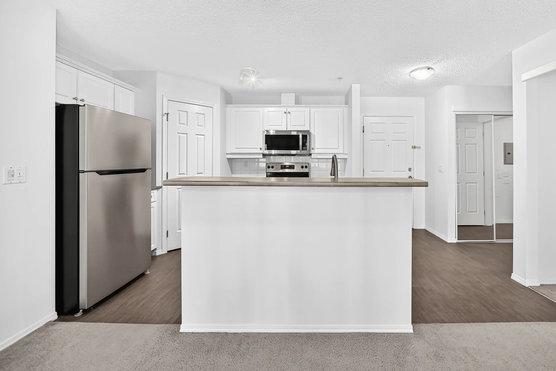 Kitchen with island breakfast bar, white cabinetry, and stainless steel appliances