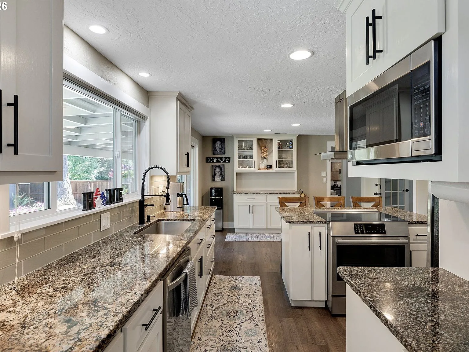 Updated kitchen with granite countertops, white cabinetry, and stainless steel appliances