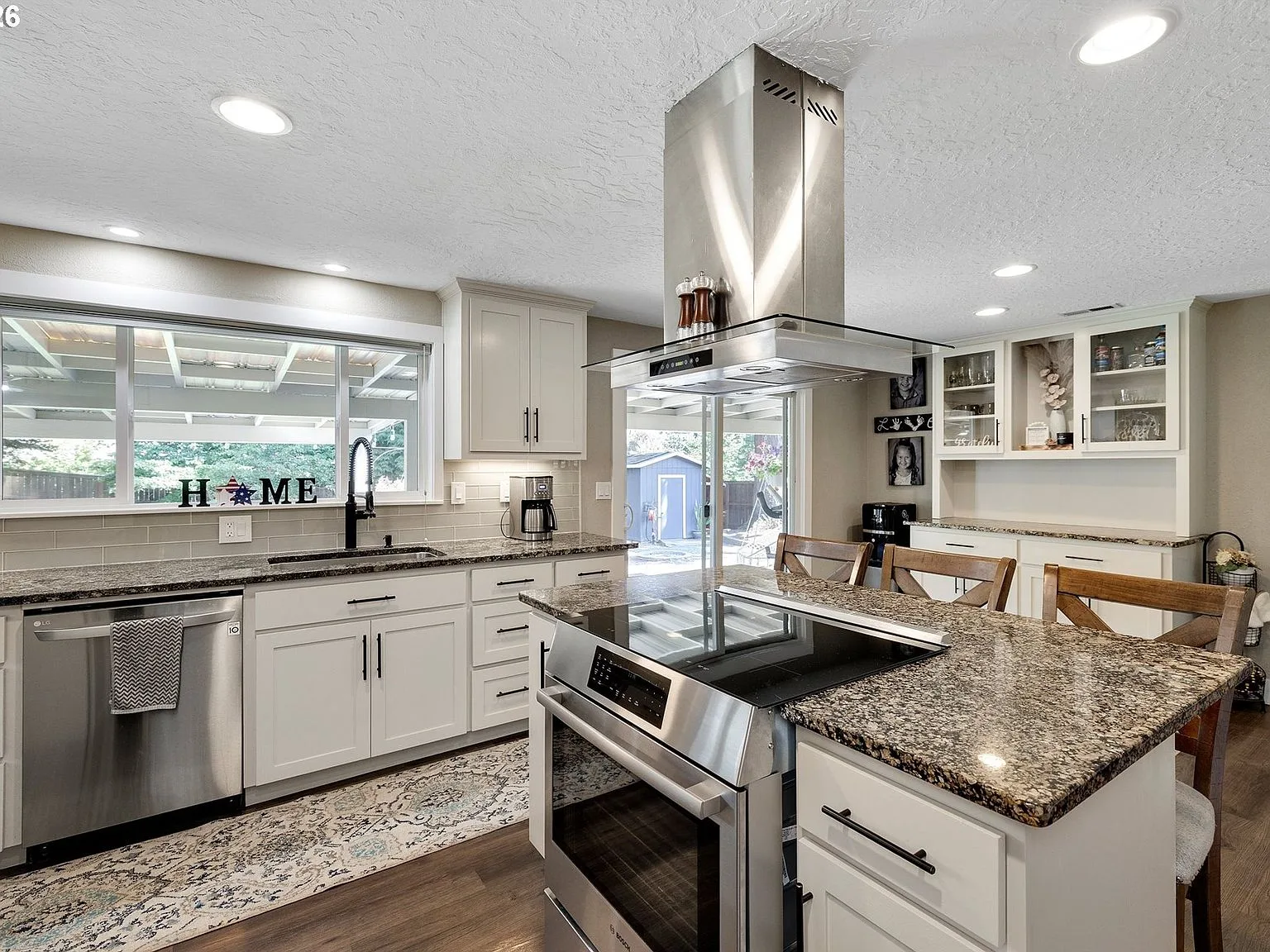 Kitchen with large central island, granite countertops, and stainless steel vent hood