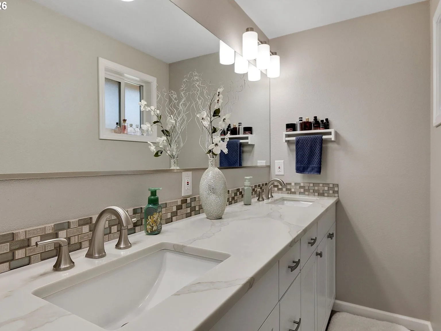 Updated primary bathroom with white cabinetry and marble-look countertops