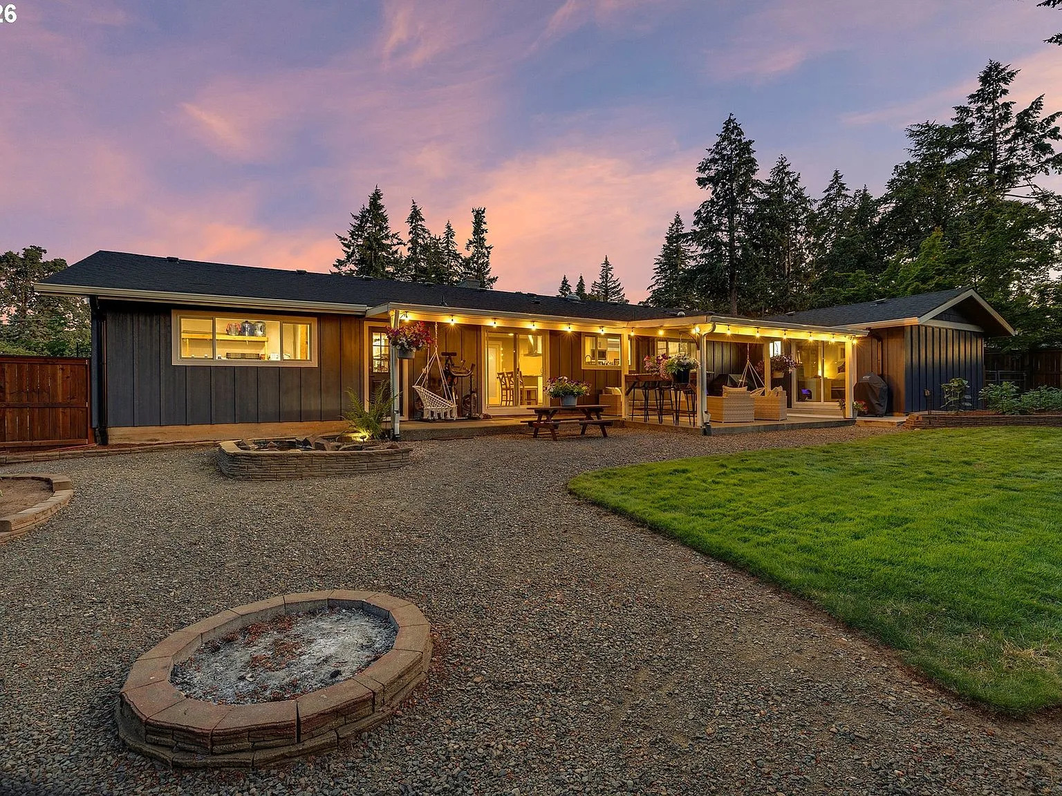 Covered backyard patio at twilight with string lights and dark grey siding