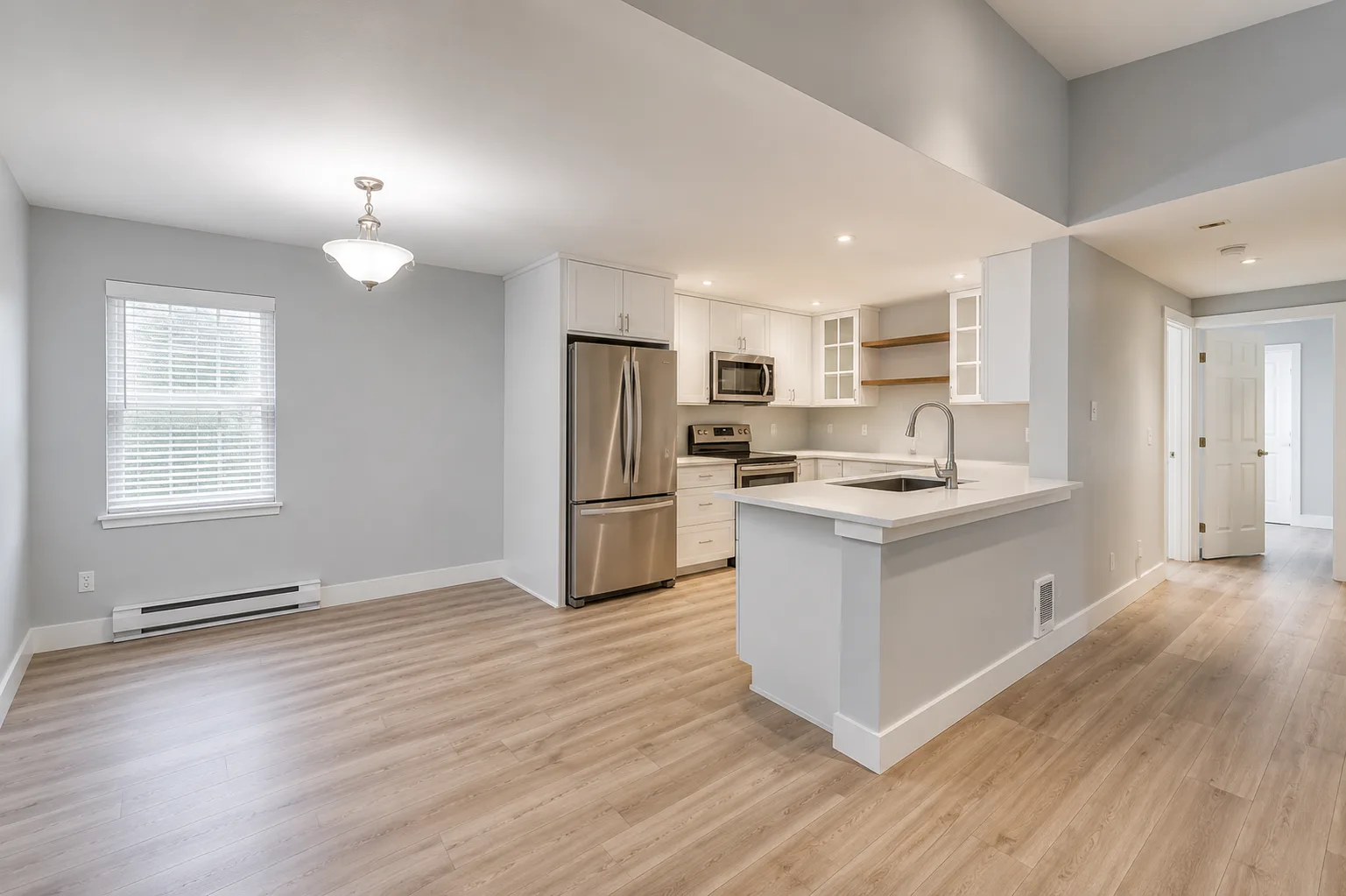 Open-concept kitchen and dining area with white cabinetry and wood-look flooring