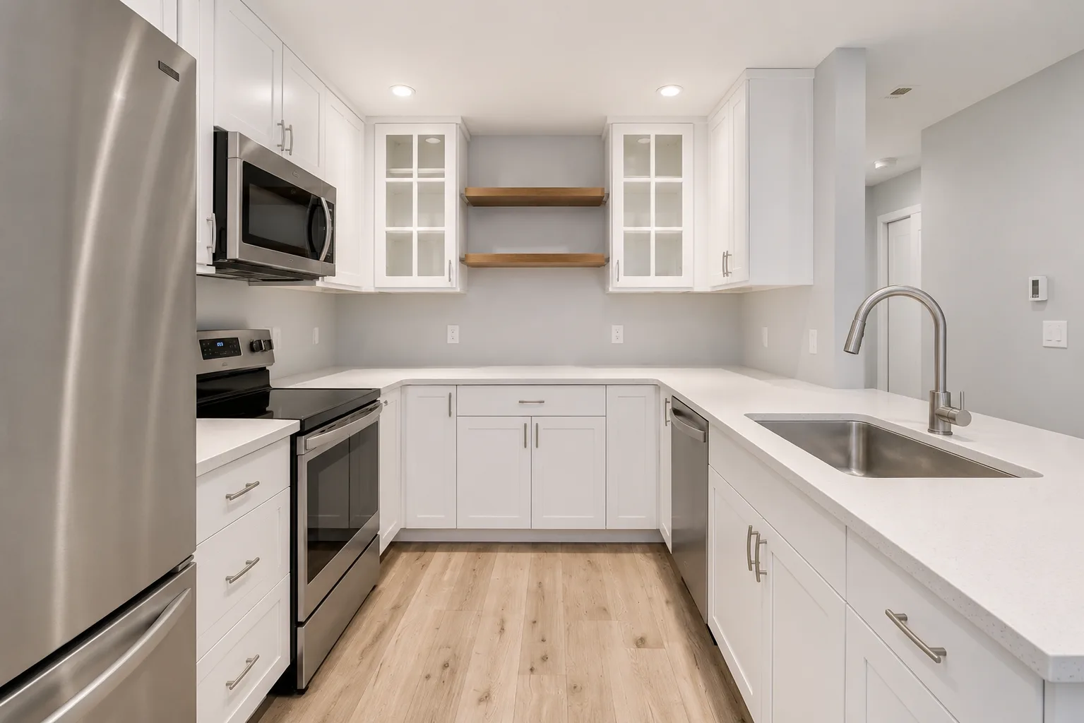 Modern condo kitchen with white cabinetry and stainless steel appliances