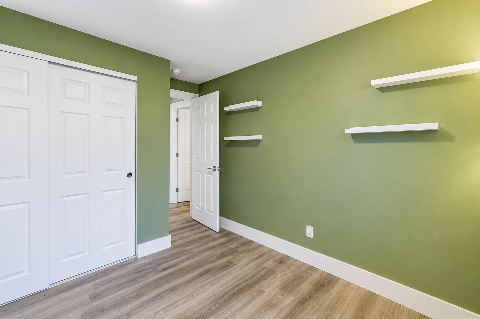 Sage green bedroom with floating wall shelves
