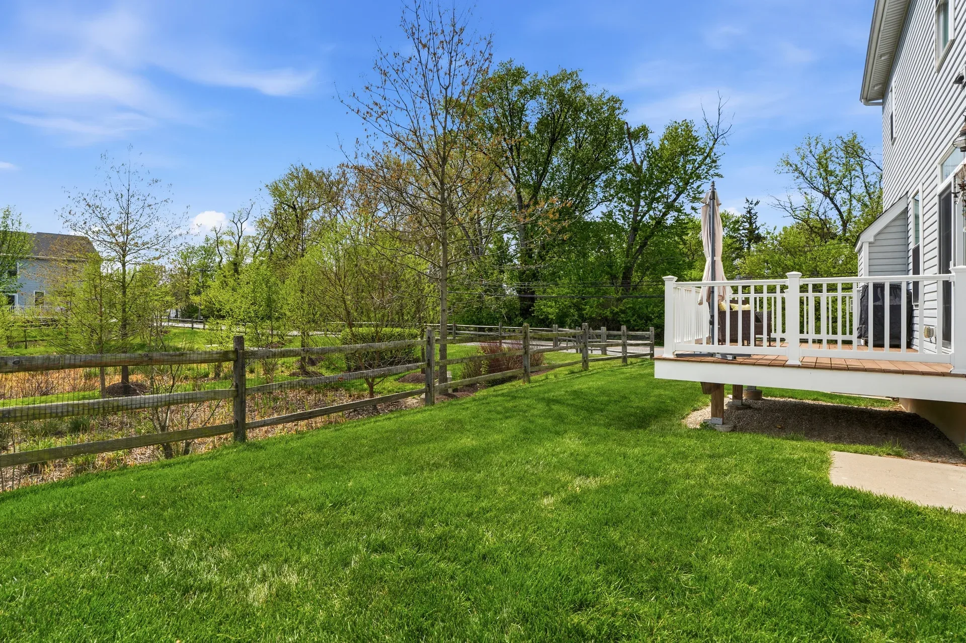 Backyard exterior view with wooden deck, lawn, and outdoor furniture