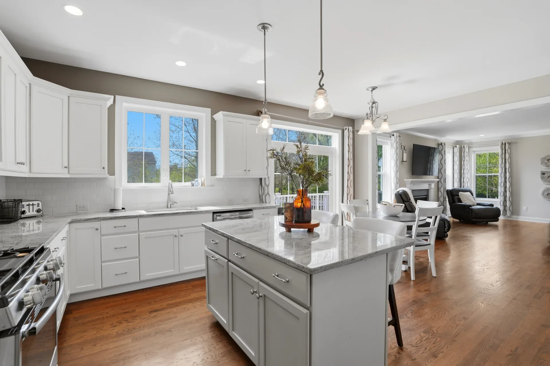 Open concept kitchen and living area with white cabinetry and hardwood floors throughout