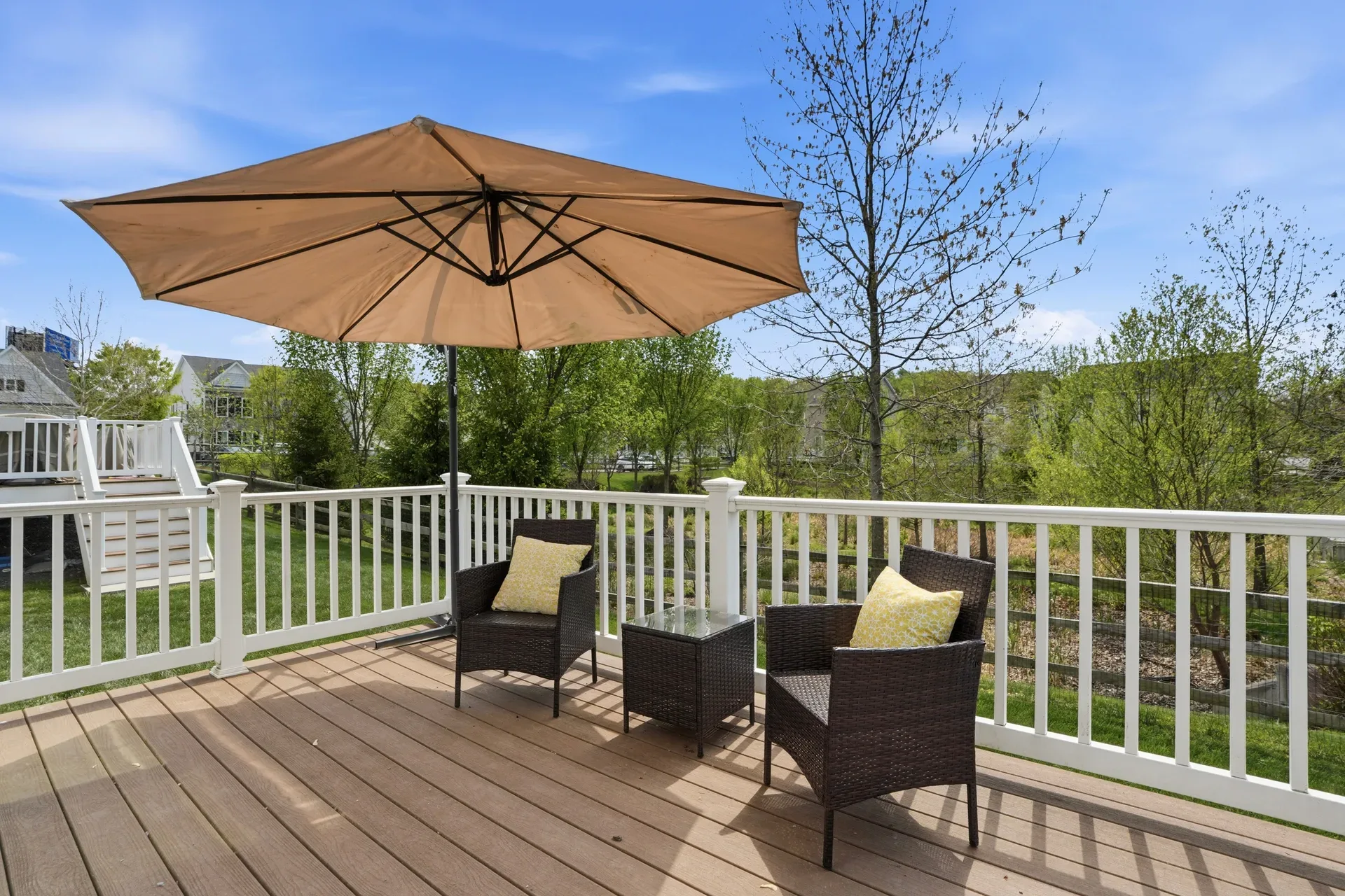 Backyard wooden deck with white vinyl railings and blue sky