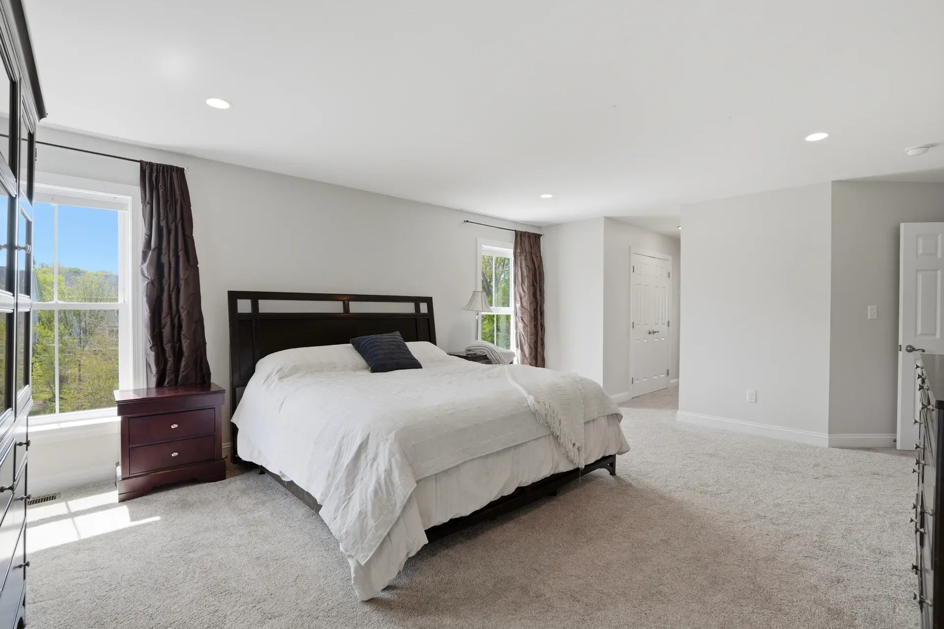 Master bedroom with light grey walls, neutral carpet, and natural daylight from side windows