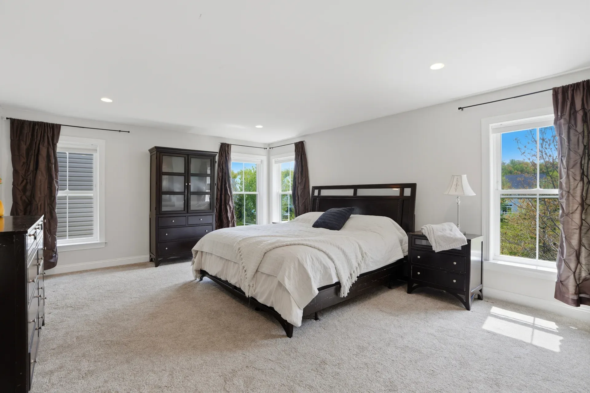 Primary suite bedroom with king bed, neutral carpet, and recessed lighting