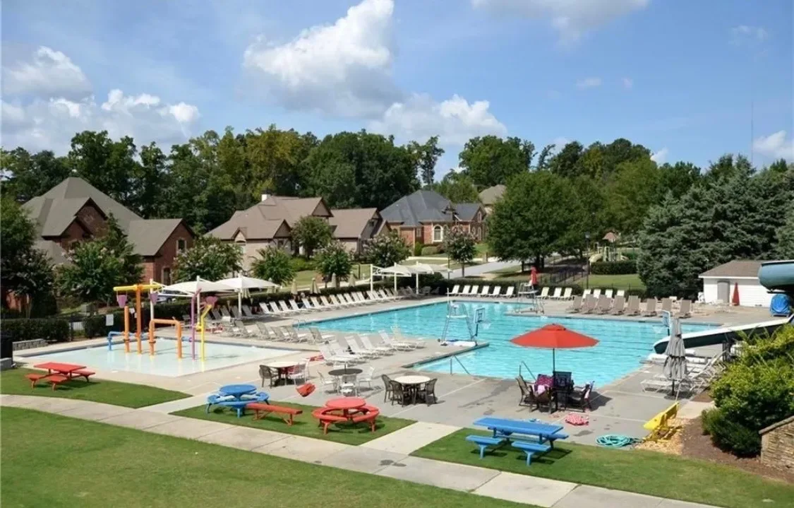 Community swimming pool surrounded by lounge chairs, an amenity maintained by the homeowners association at Chateau Elan
