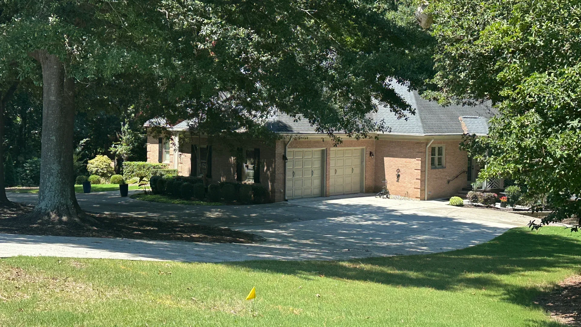 5720 Golf Club Dr, angled front and side view of brick house with two-car garage, wooded setting, and manicured lawn in The Legends at Chateau Elan, Braselton Georgia