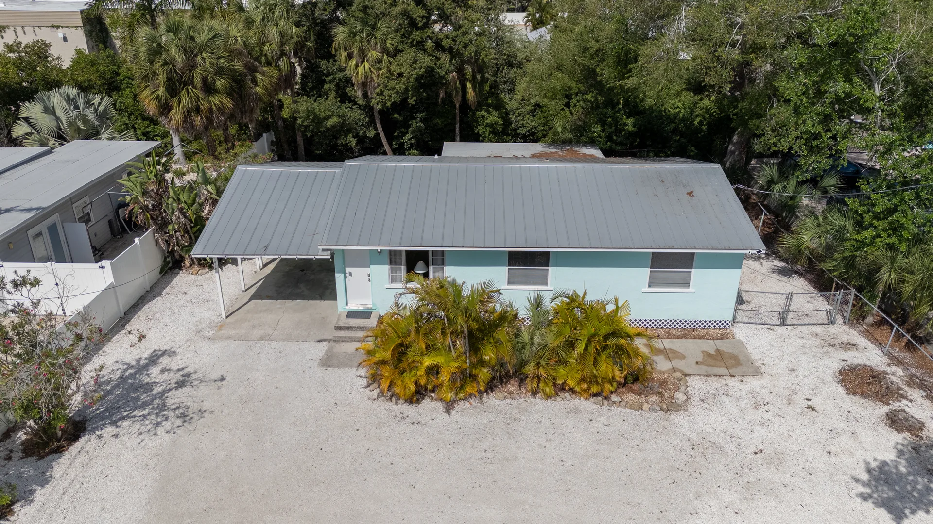 Aerial view of 5026 Calle Minorga in Sarasota, Florida showing the exterior facade, metal roof, and tropical landscaping of this Siesta Key cottage