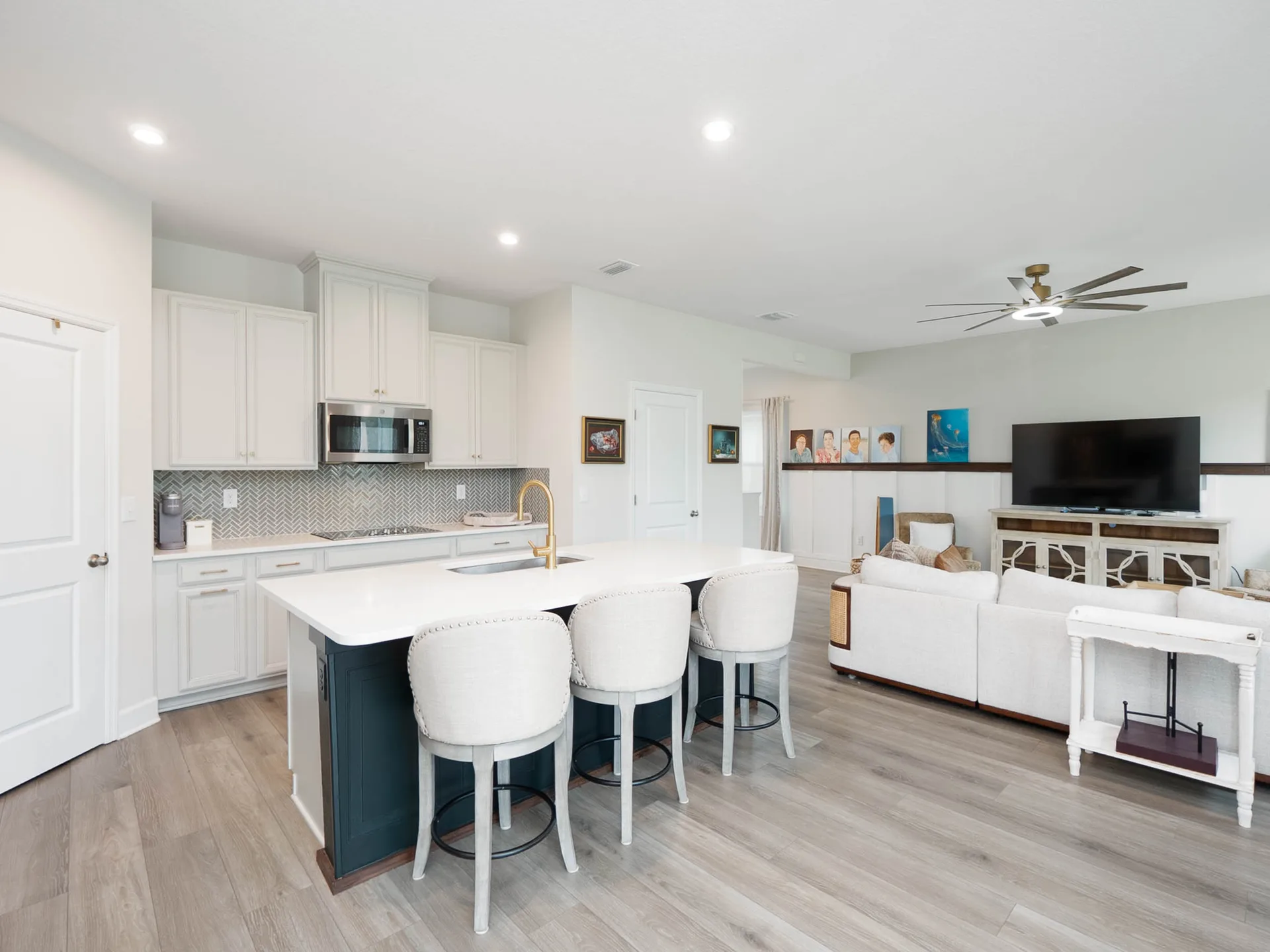 Bright open-concept kitchen and living area with modern finishes, stone countertops, and stainless steel appliances in a 2024-built Florida home