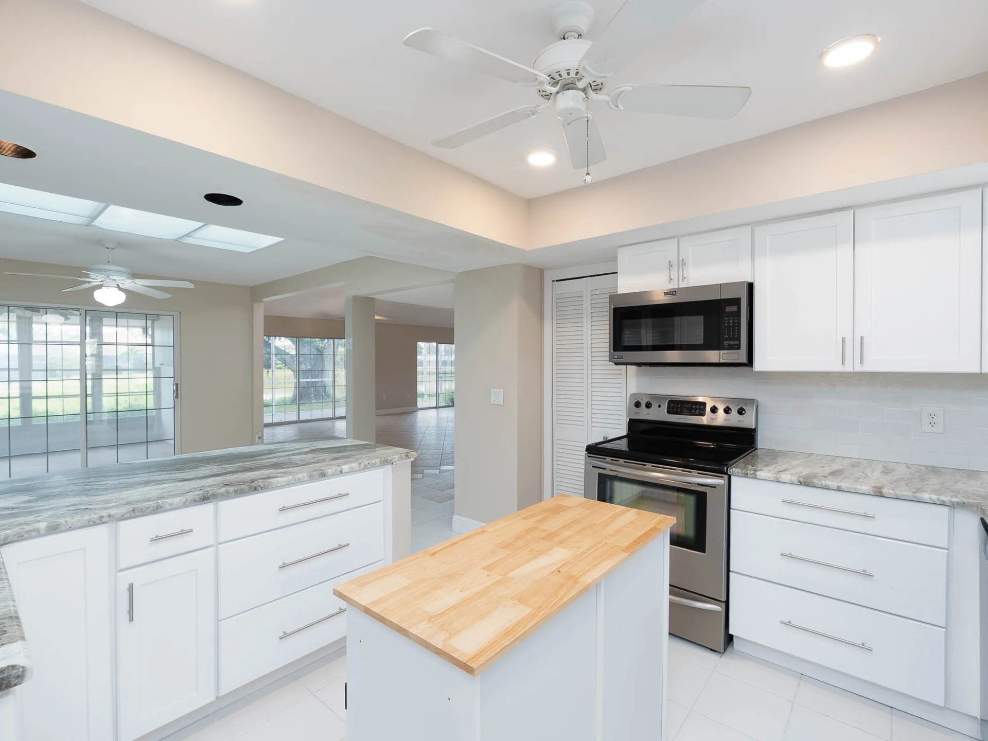 White kitchen island with counter seating at 1141 Sleepy Hollow Court in Venice, Florida, featuring light cabinetry and tile flooring