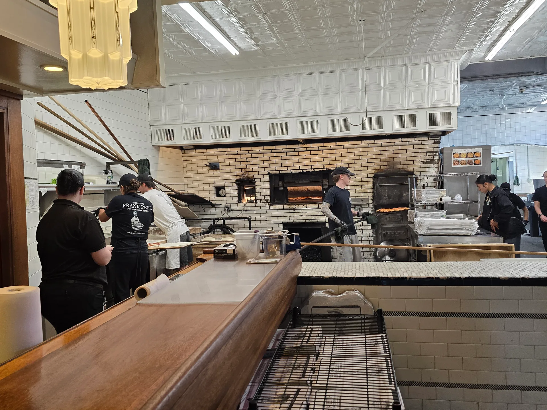 A pizza maker works the coal-fired oven at Pepe's