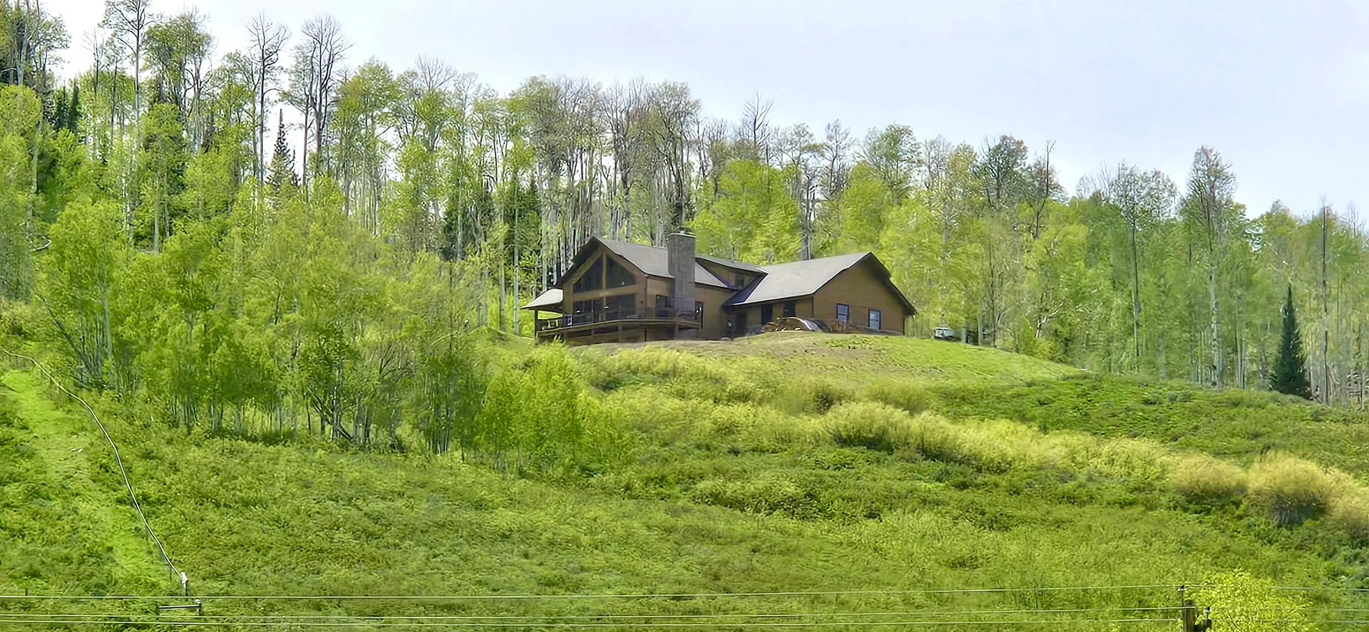 Mountain home facade nestled on a hillside with steep rooflines and deck