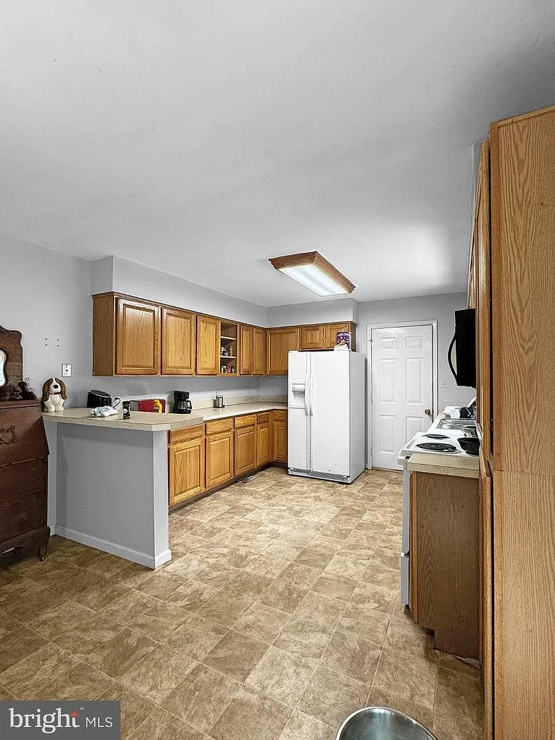 Kitchen with oak cabinetry, appliances, and laminate countertops