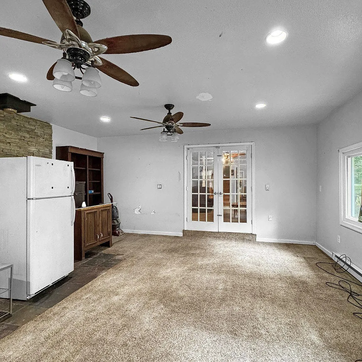 Large carpeted living area with recessed lighting and ceiling fans