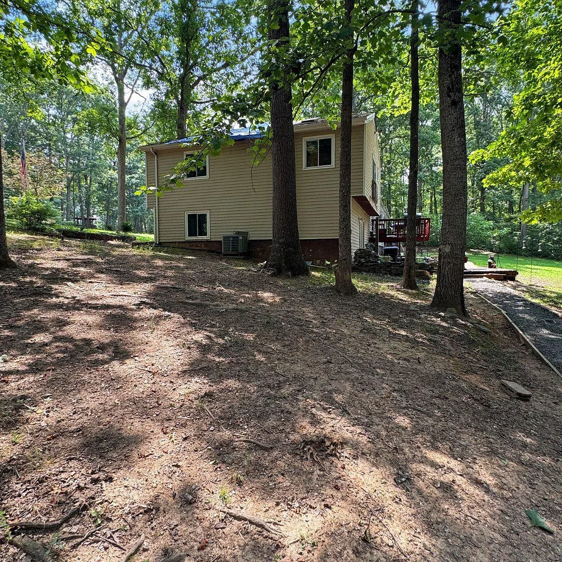Side yard with gravel path leading to back deck through trees