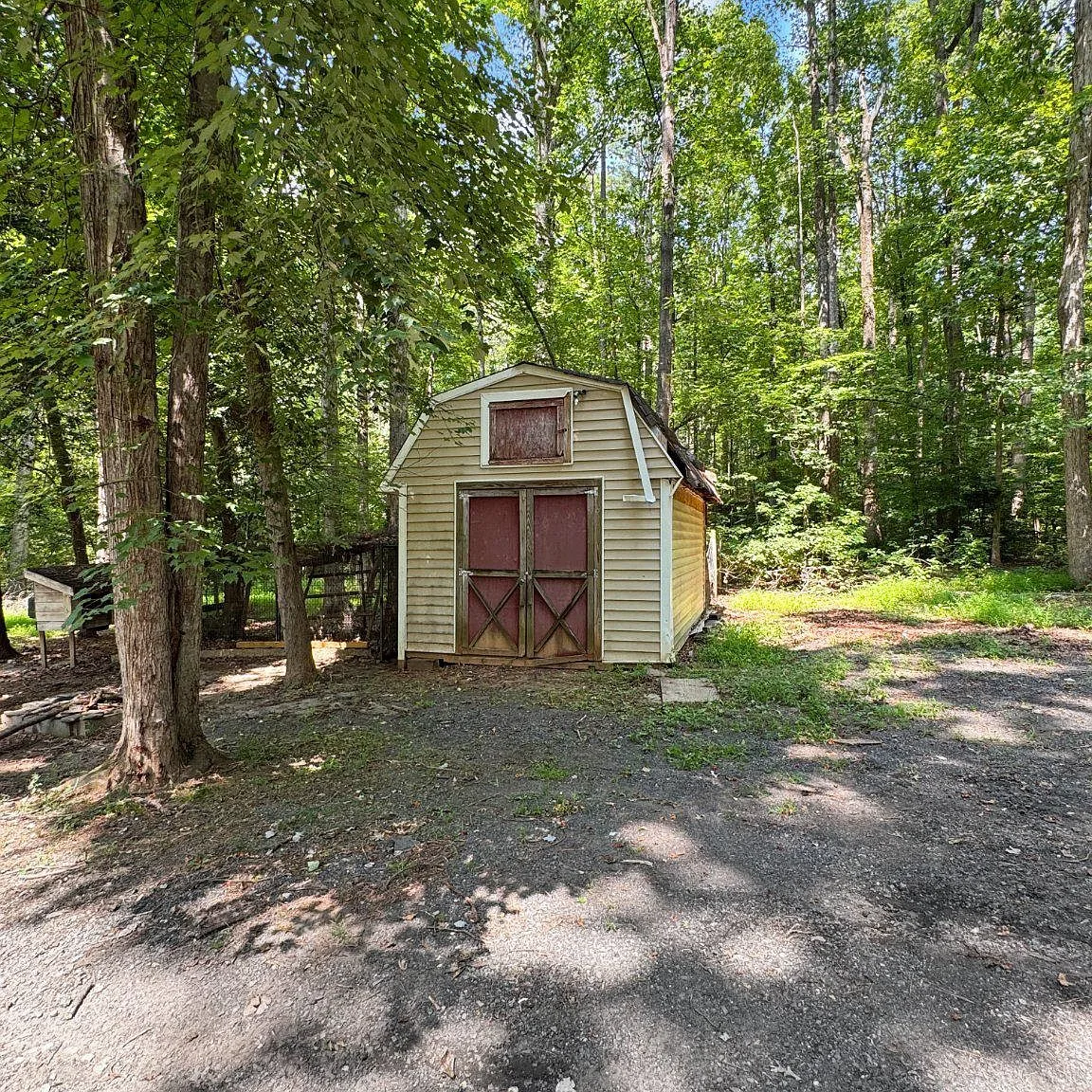 Storage shed with gambrel roof and red barn-style doors