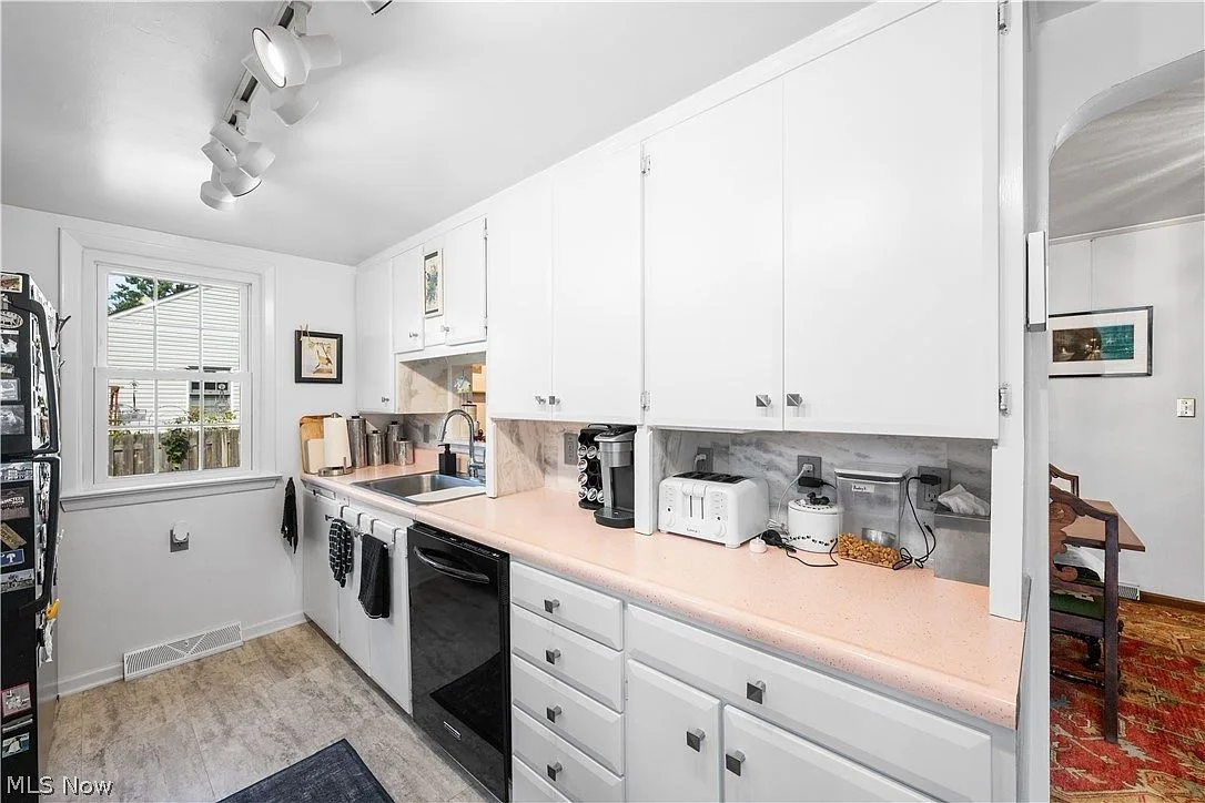 Galley kitchen looking toward sink area with white cabinets