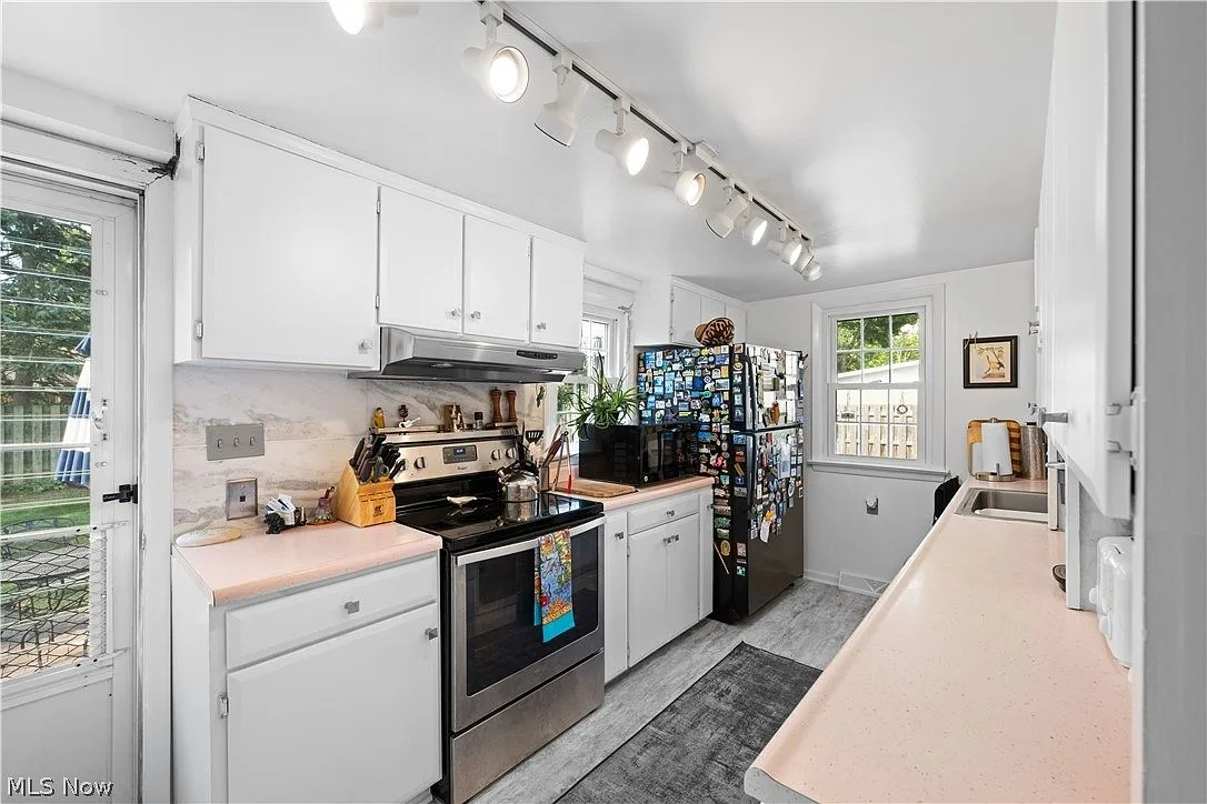 Galley kitchen with white cabinetry and stainless steel appliances
