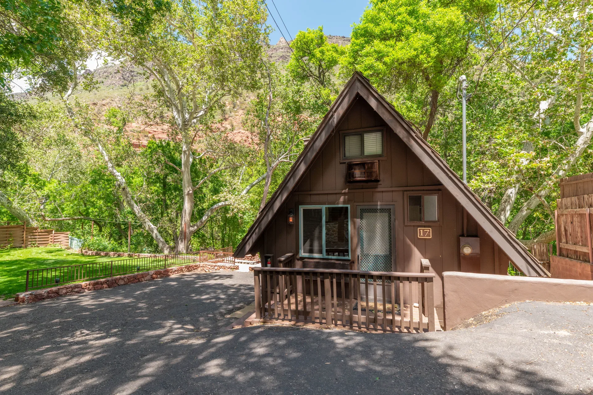 Standalone A-frame cabin with natural wood deck under mature trees