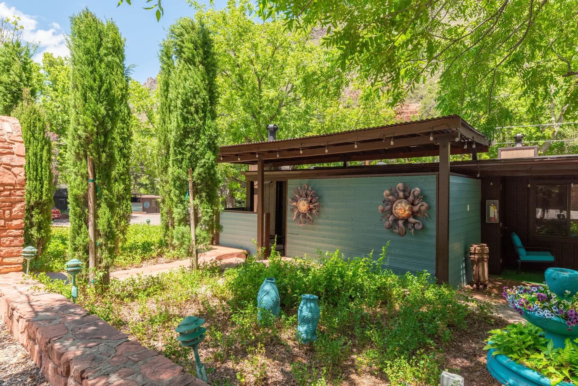 Resort building exterior with teal wood siding and Italian cypress