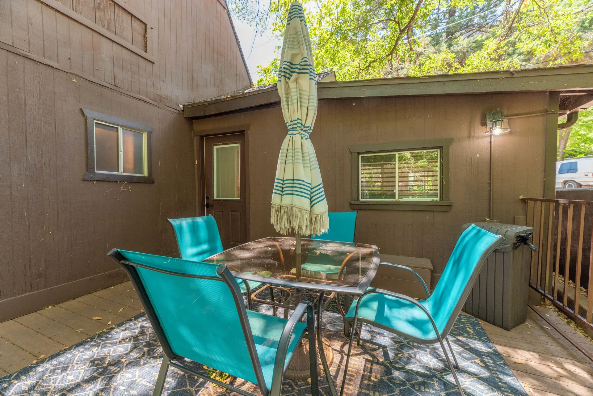 Ground-level patio with teal chairs and outdoor rug