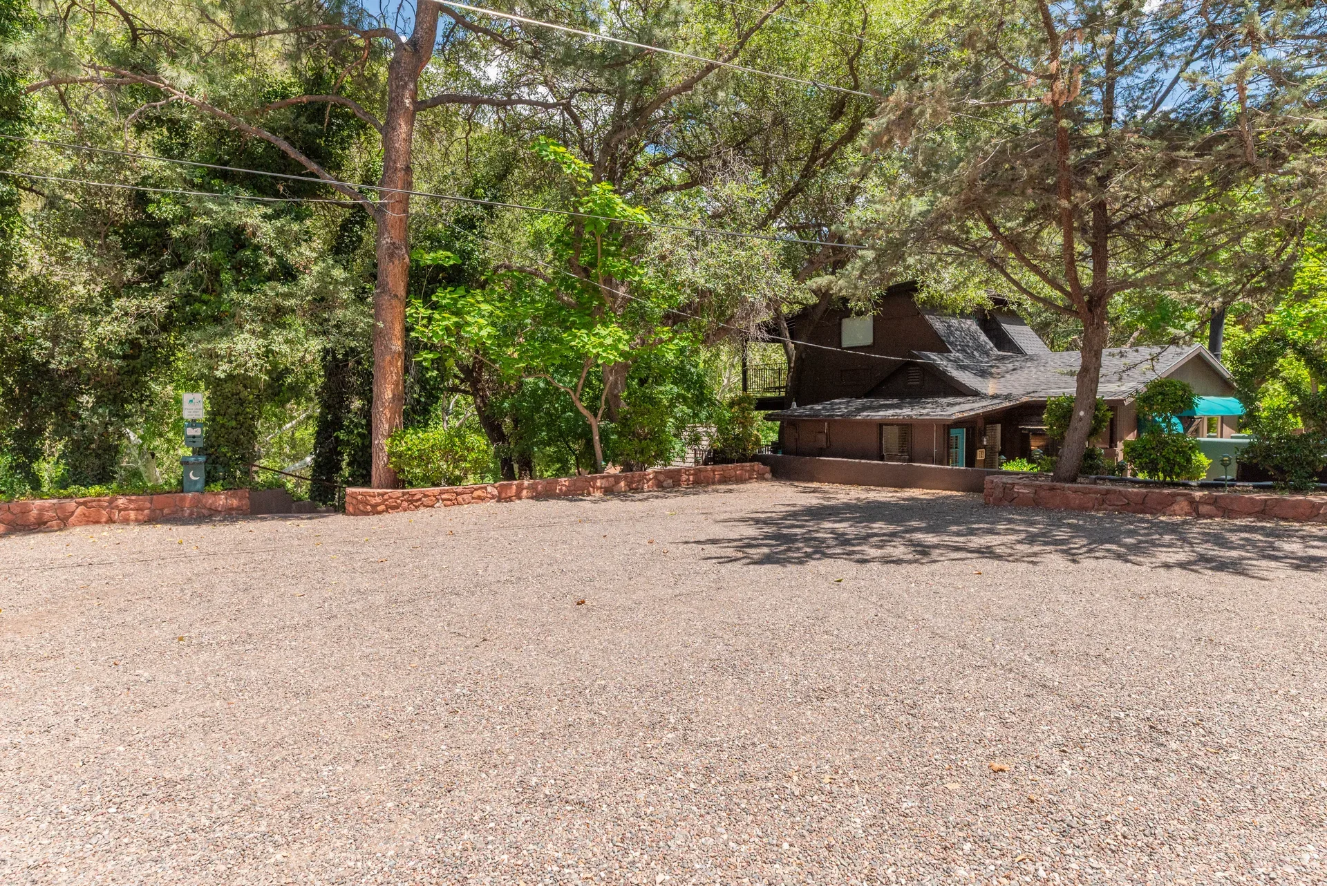 Gravel parking lot shaded by mature pine trees