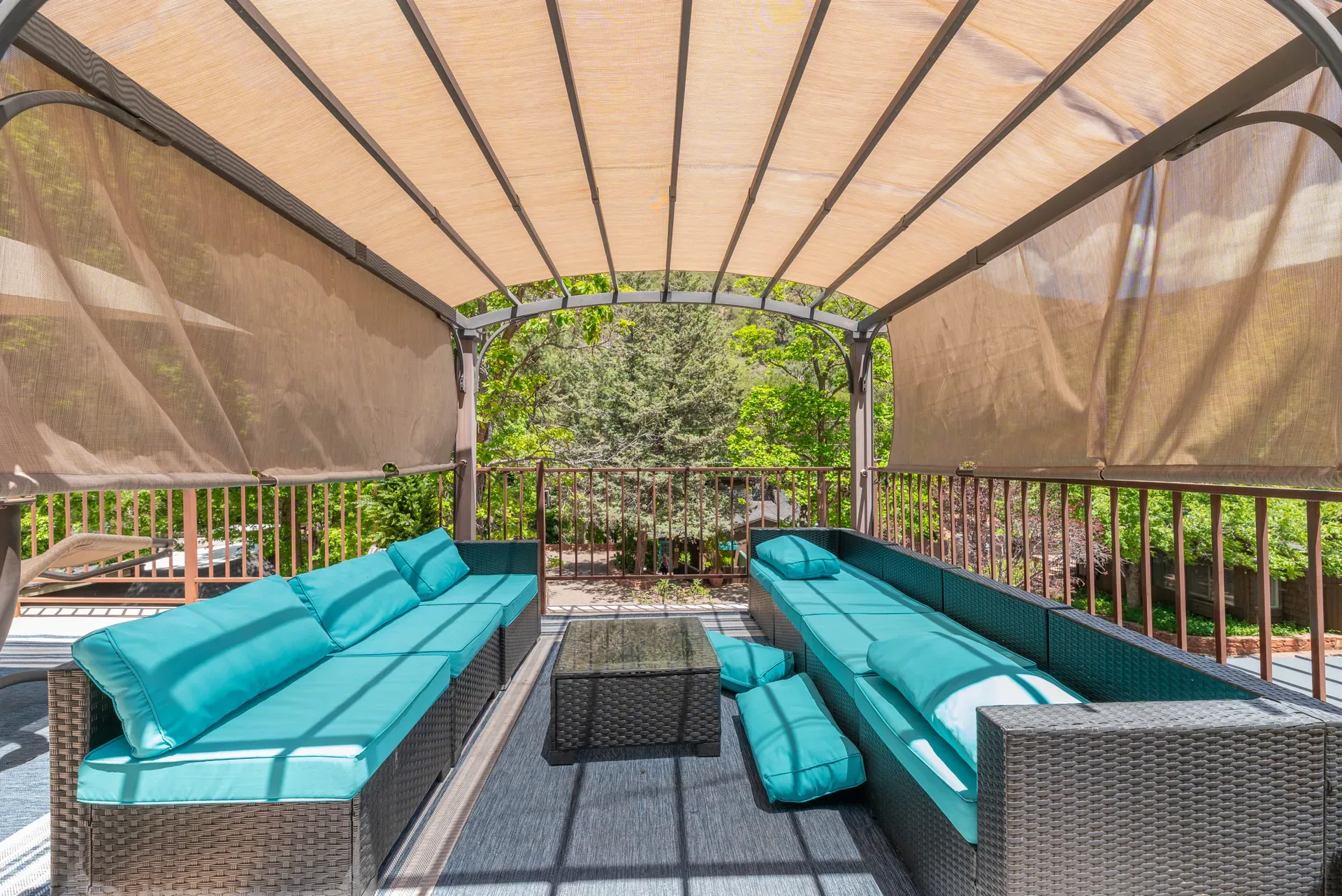 Shaded deck with sectional couches and teal cushions