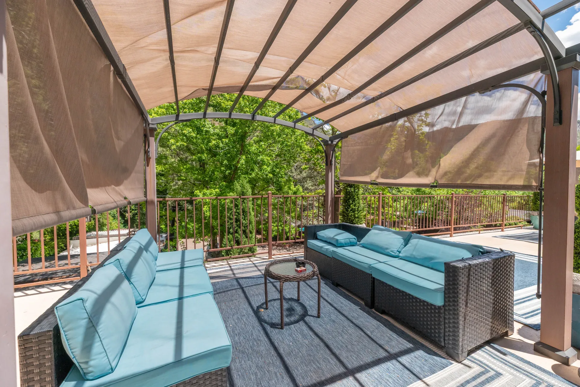 Outdoor lounge area with rattan sofas under metal pergola