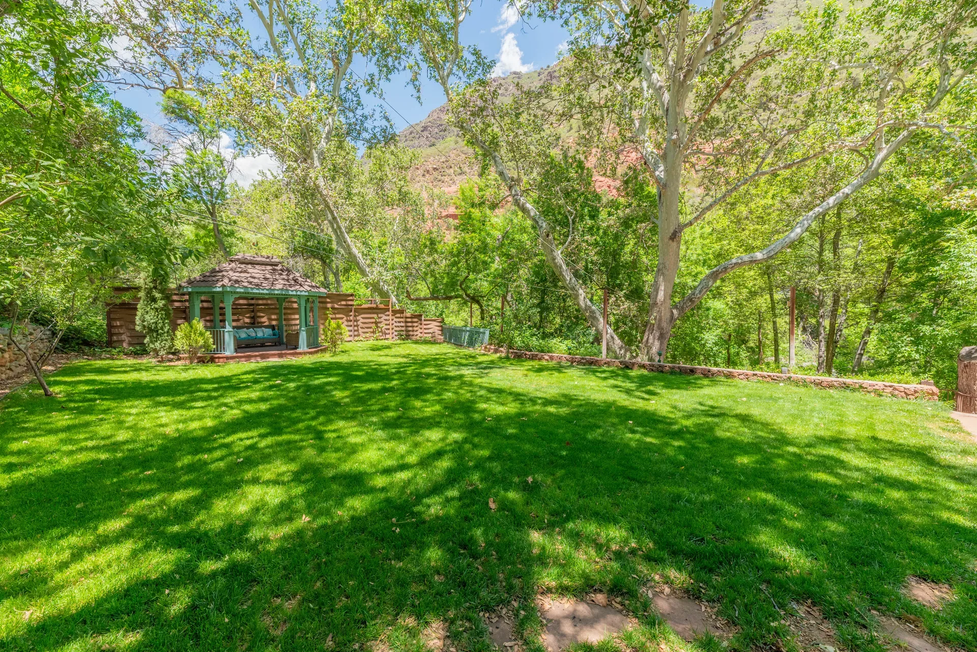 Backyard lawn area with mature sycamore trees and gazebo