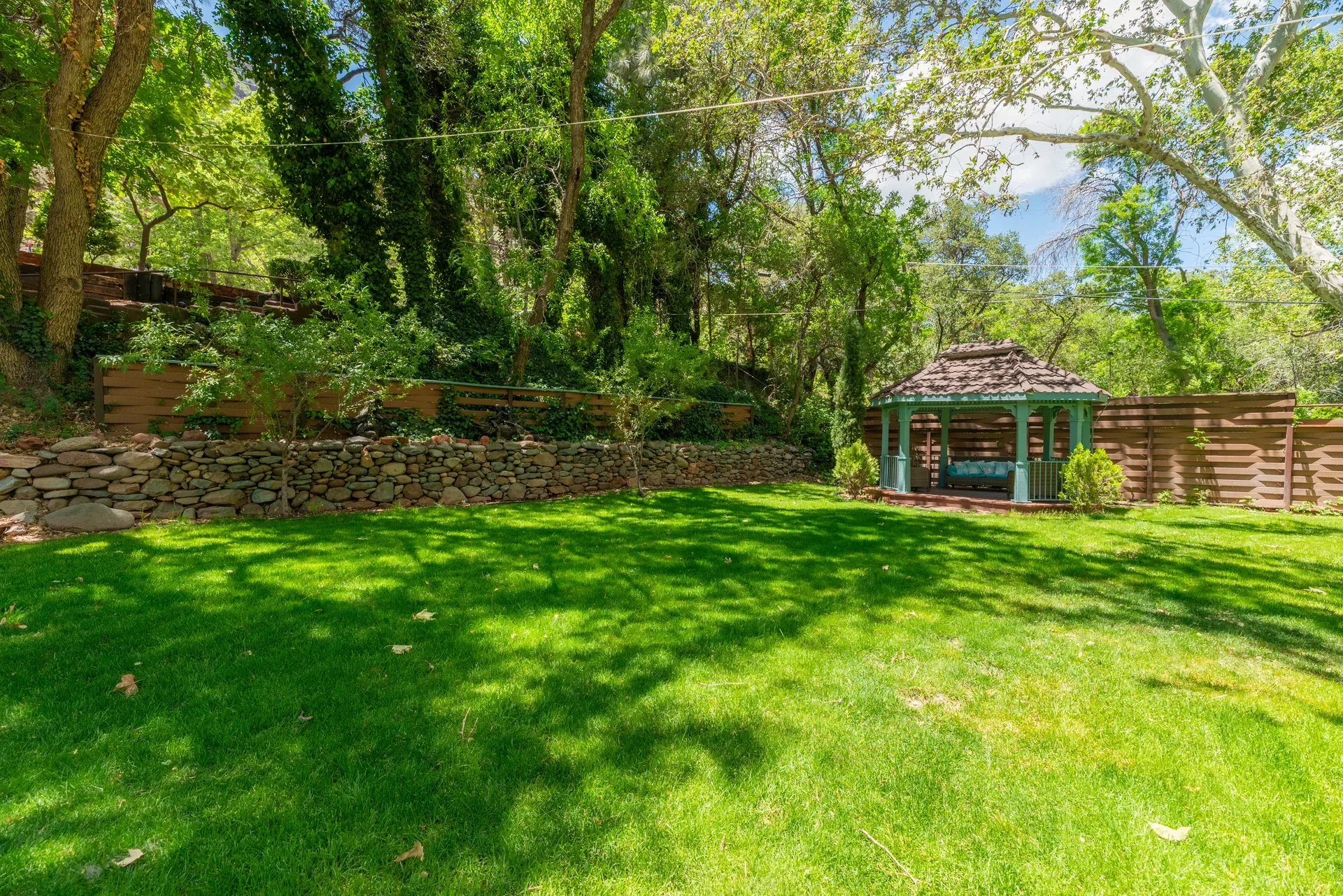Manicured lawn with decorative gazebo and wood fencing