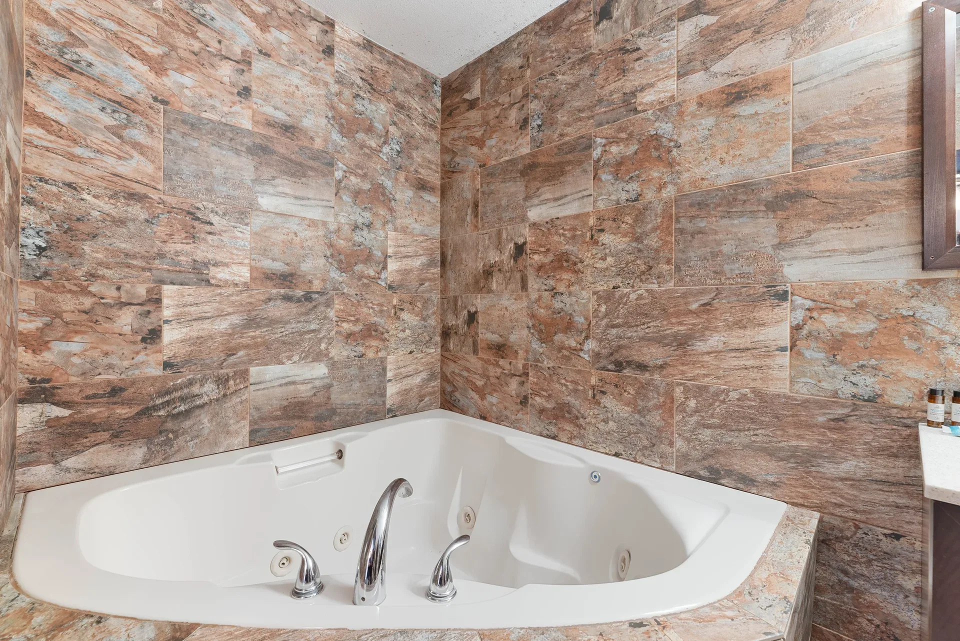 Bathroom with jetted corner soaking tub and stone tile surround