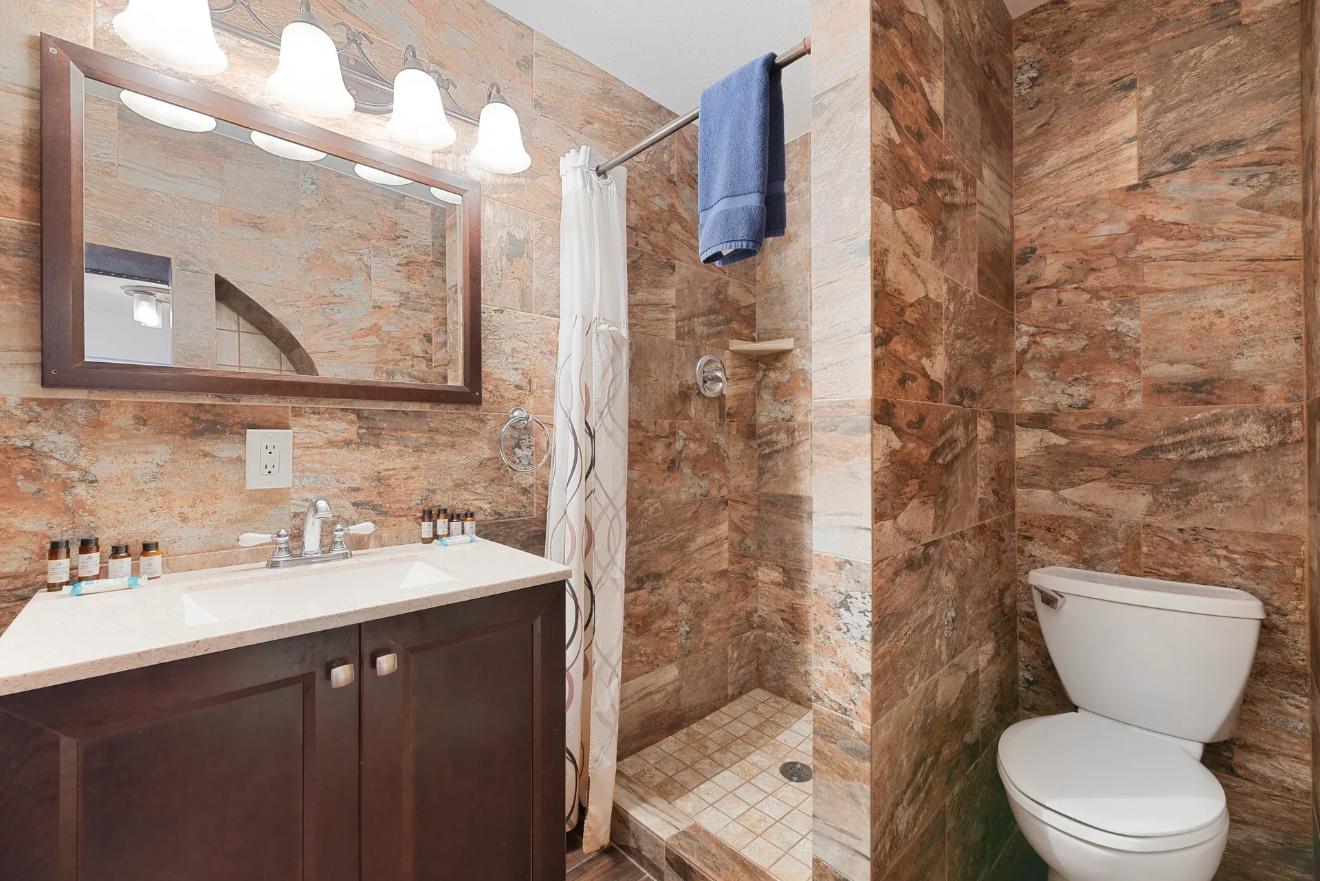 Bathroom with natural stone tiled walls and dark wood vanity