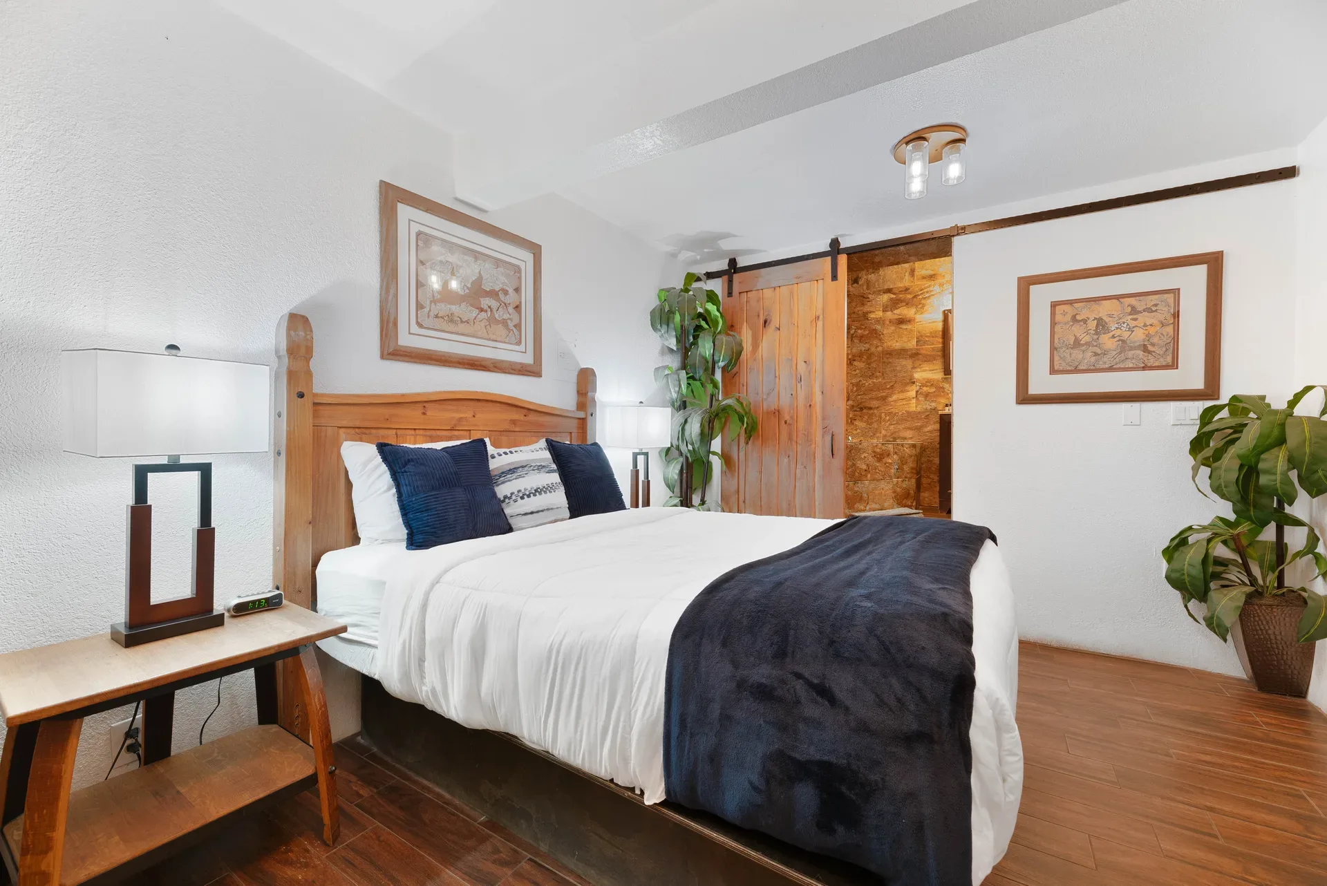Guest bedroom with wood flooring and sliding barn door