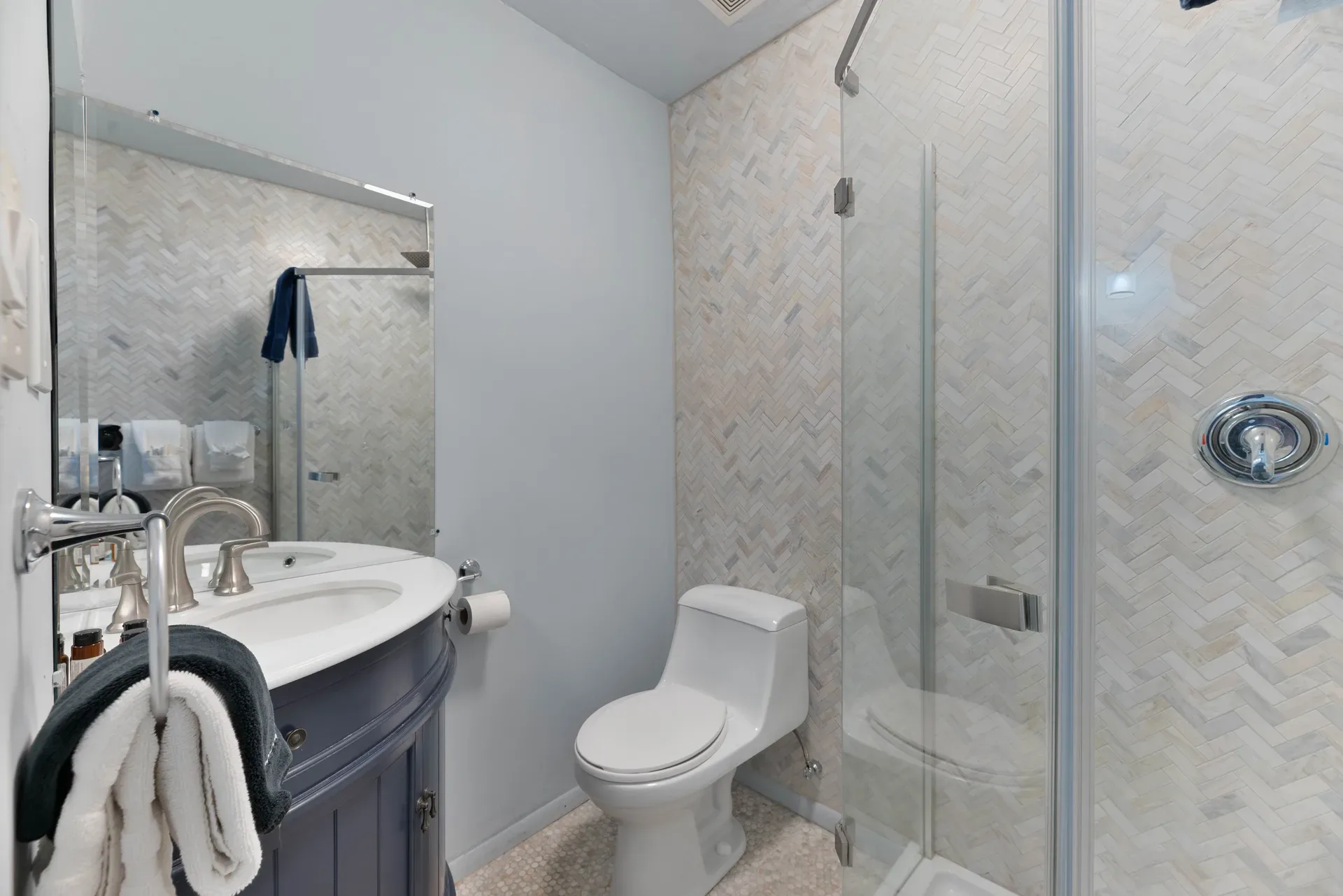 Modern luxury bathroom with herringbone tile and glass shower